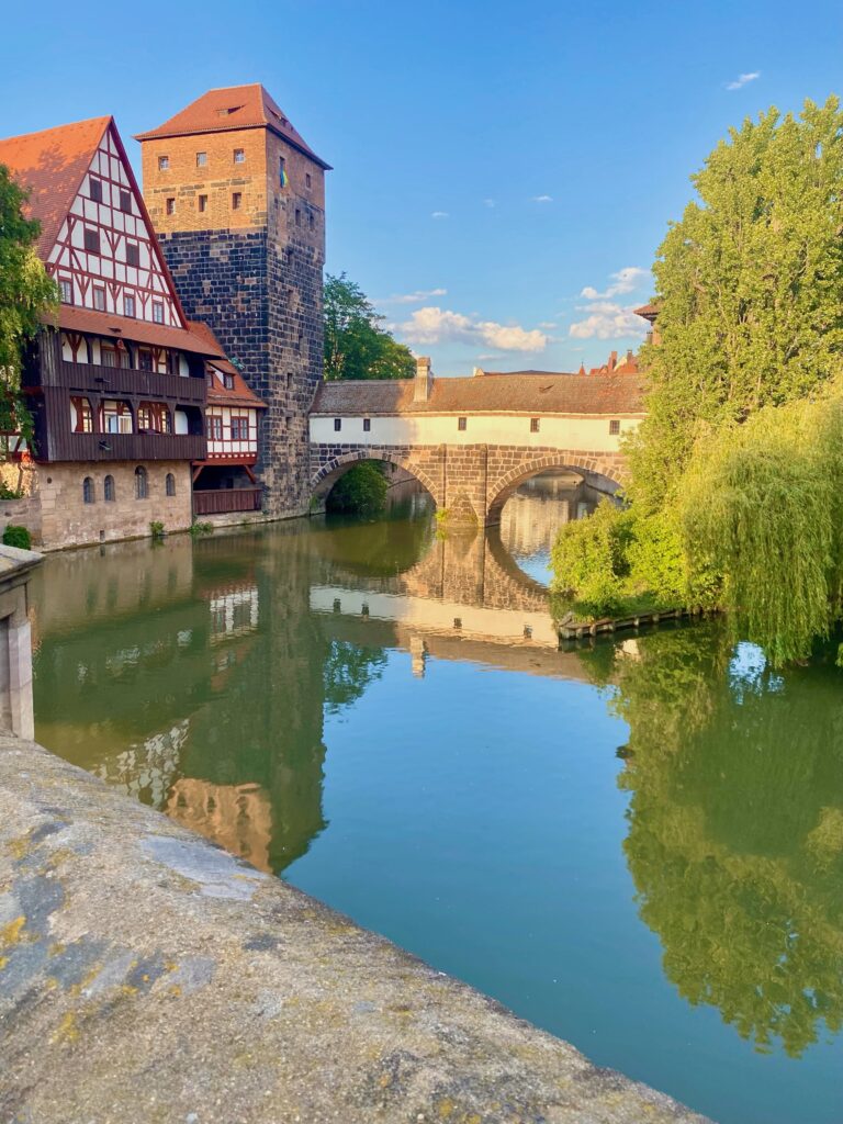 A building next to a river with a tree in Munich Germany.